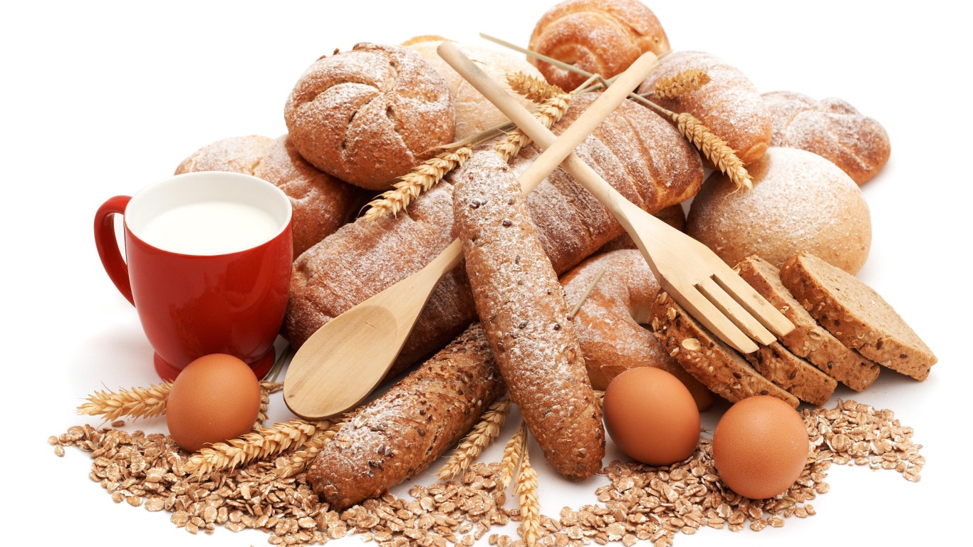 Свежий хлеб на белом фоне с яйца, чашкой молока и овсянкой