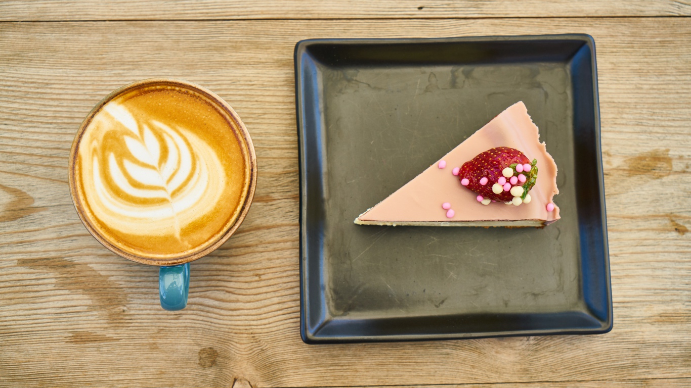 Кусок торта на черной тарелке с кофе