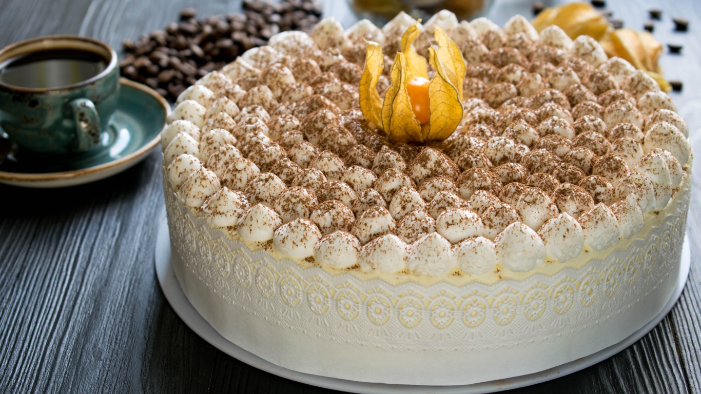 Красивый праздничный торт с цветком физалиса на столе с кофе