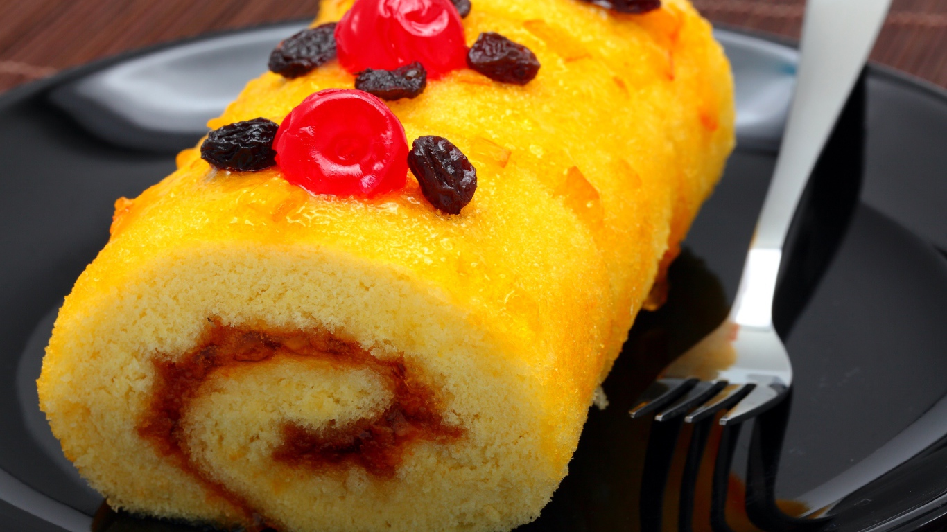 Бисквитный рулет с сухофруктами на тарелке с вилкой