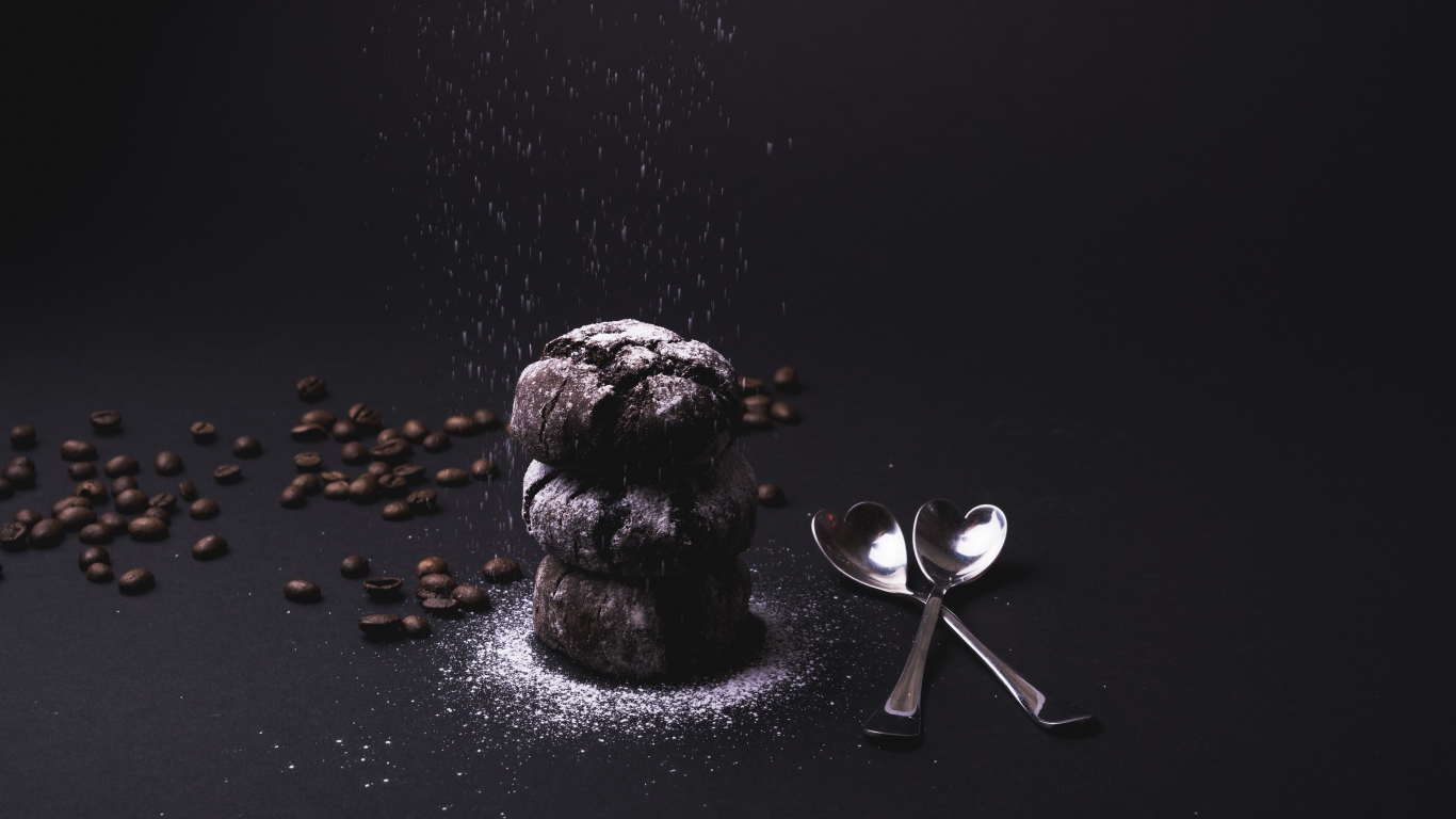 Шоколадное печенье с сахарной пудрой на черном фоне с кофейными зернами