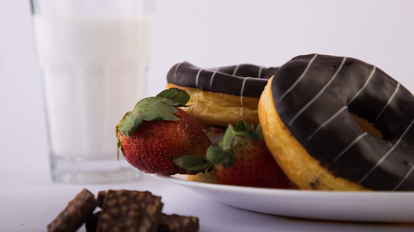 Пончики с шоколадной глазурью на тарелке с клубникой