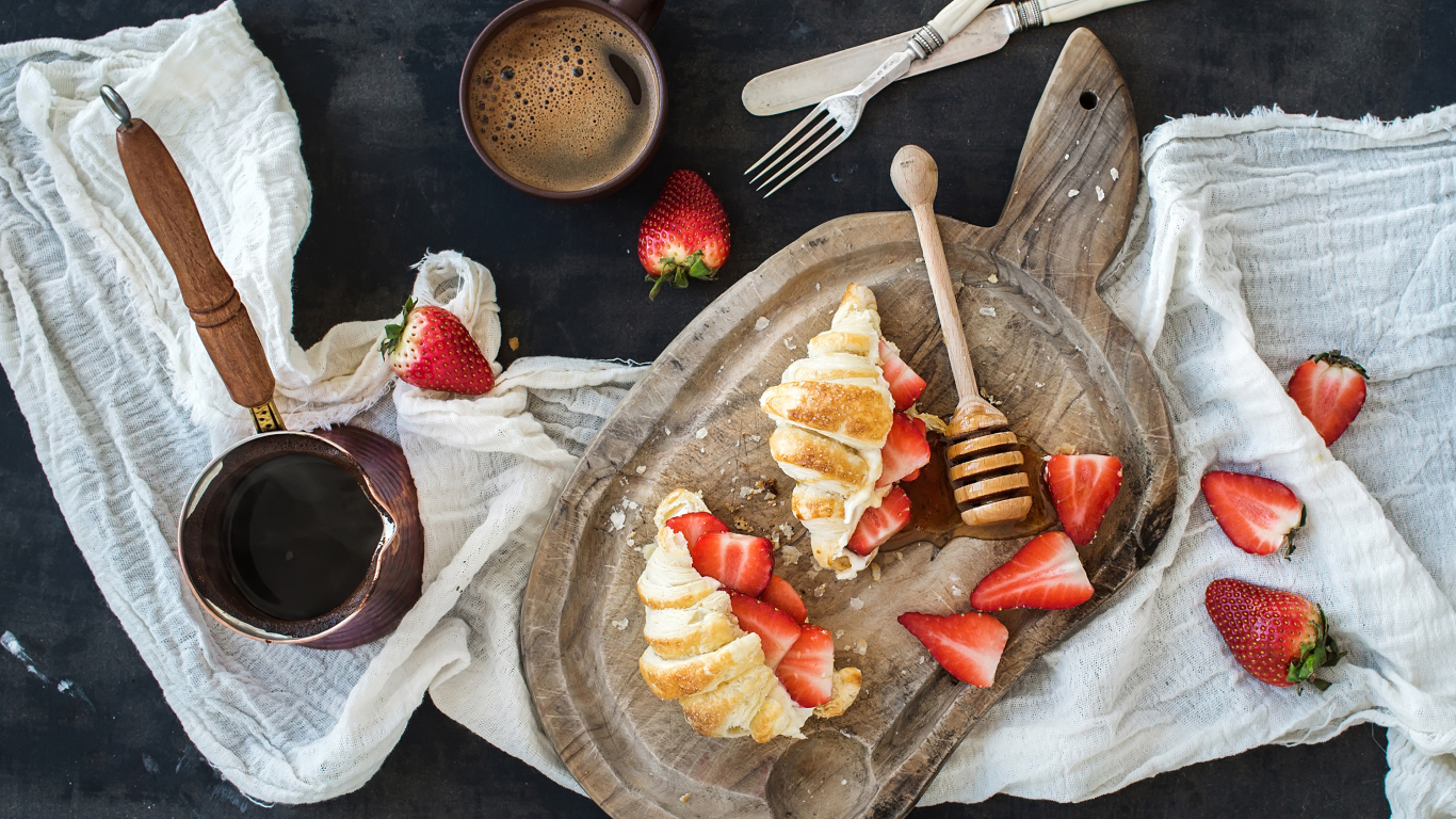 Круассаны на доске с клубникой и медом