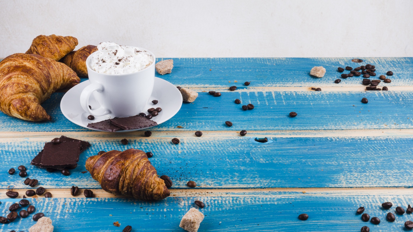 Круассаны на столе с напитком и шоколадом