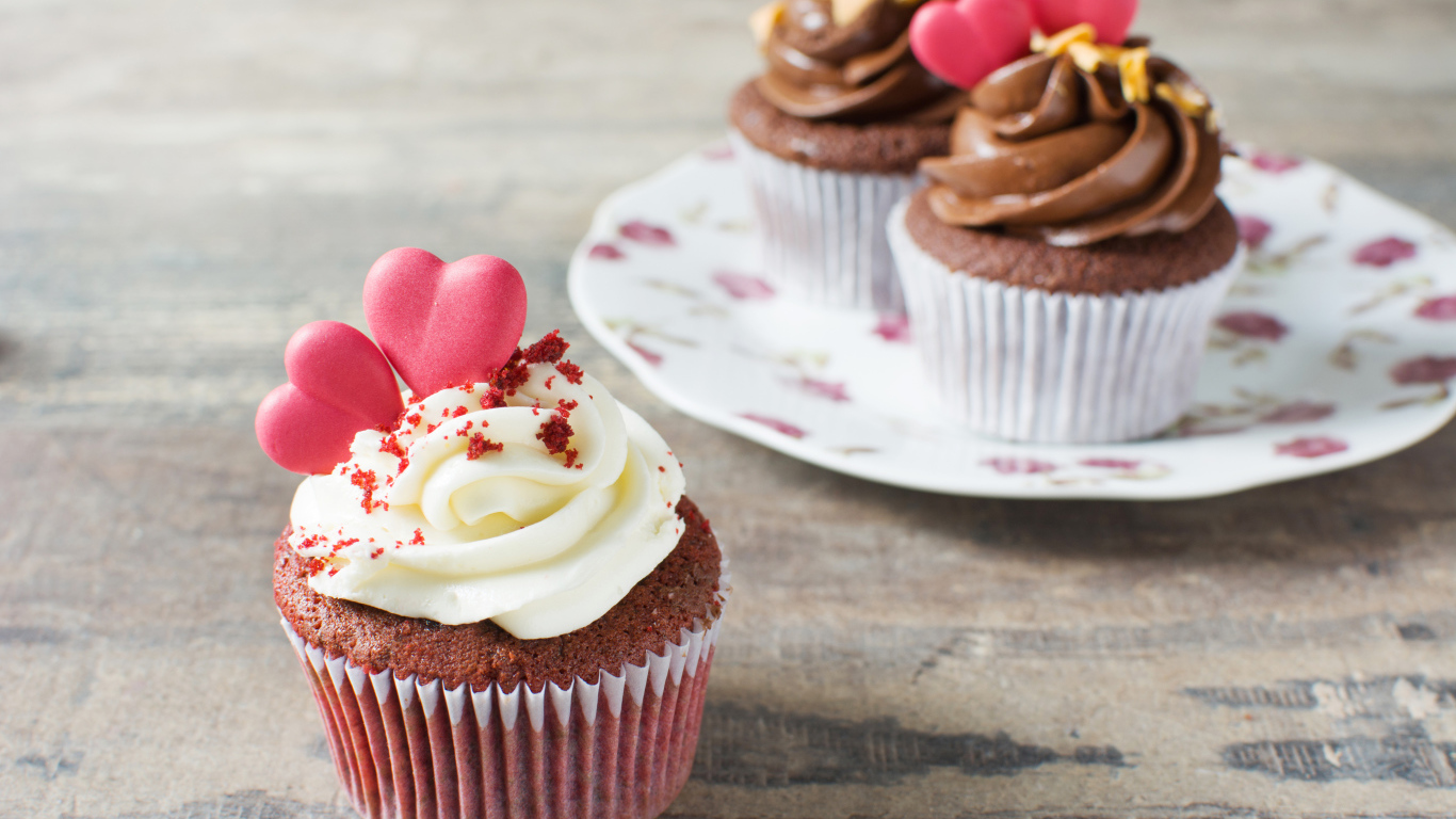 Кекс с кремом и красными сердечками на столе 