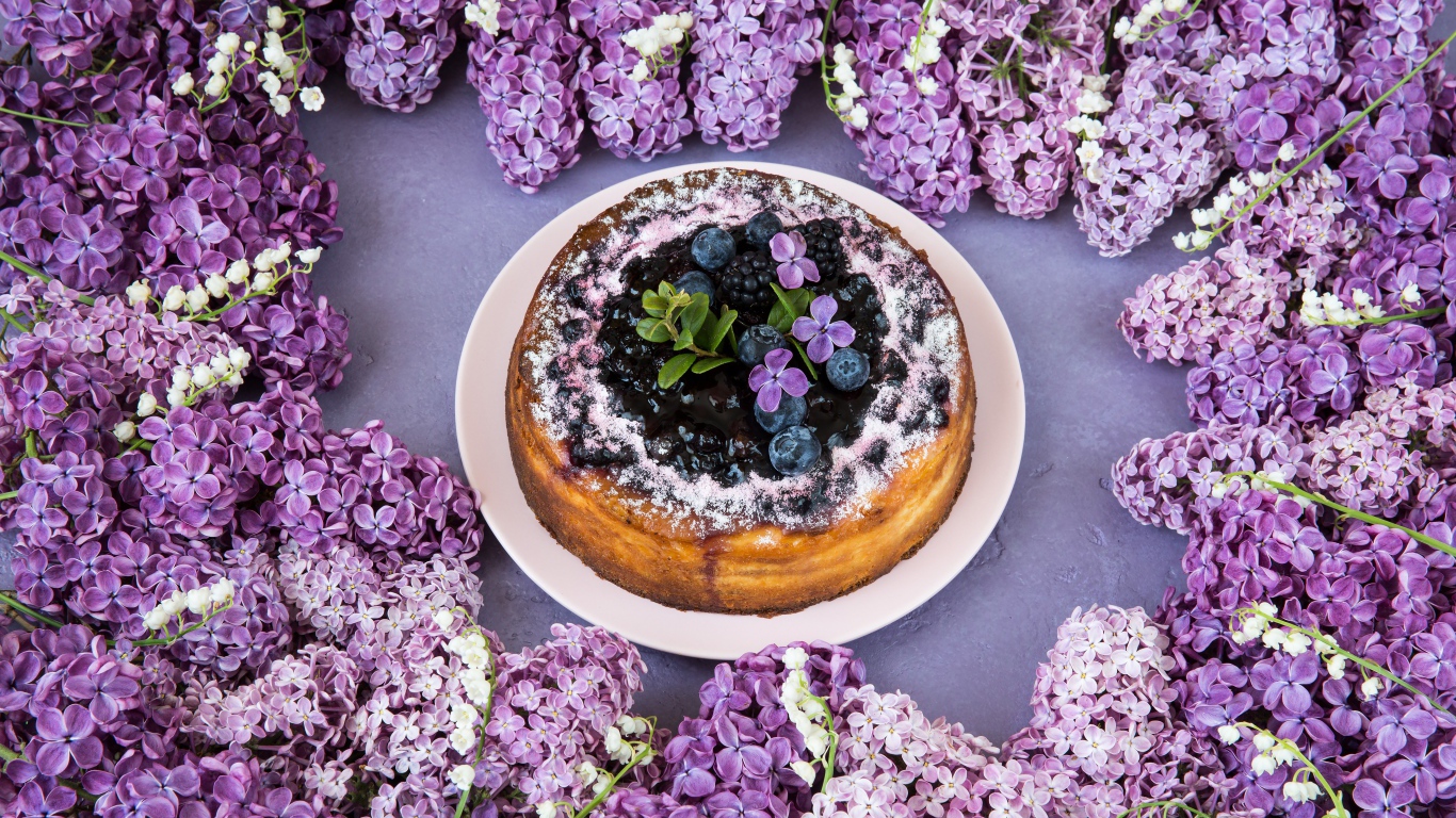Аппетитный пирог с ягодами на столе с цветами сирени