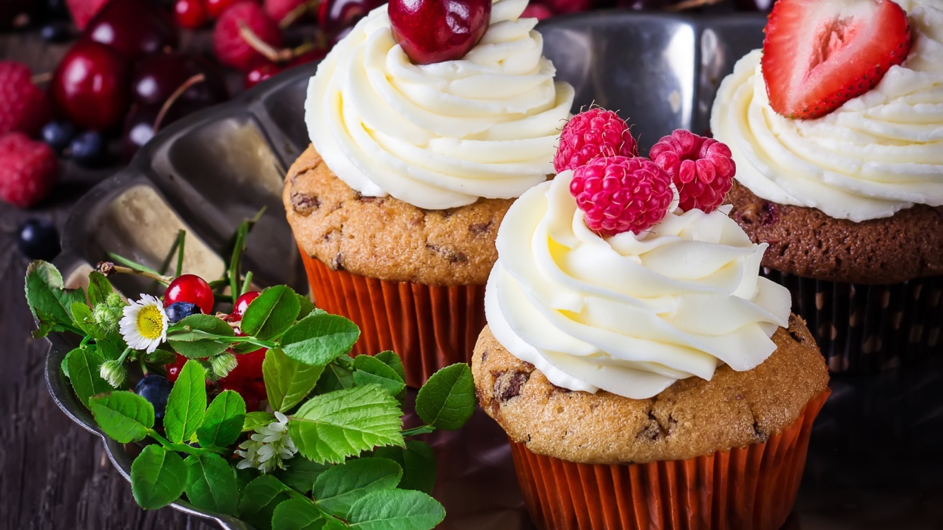 Аппетитные кексы с кремом и ягодами на блюде