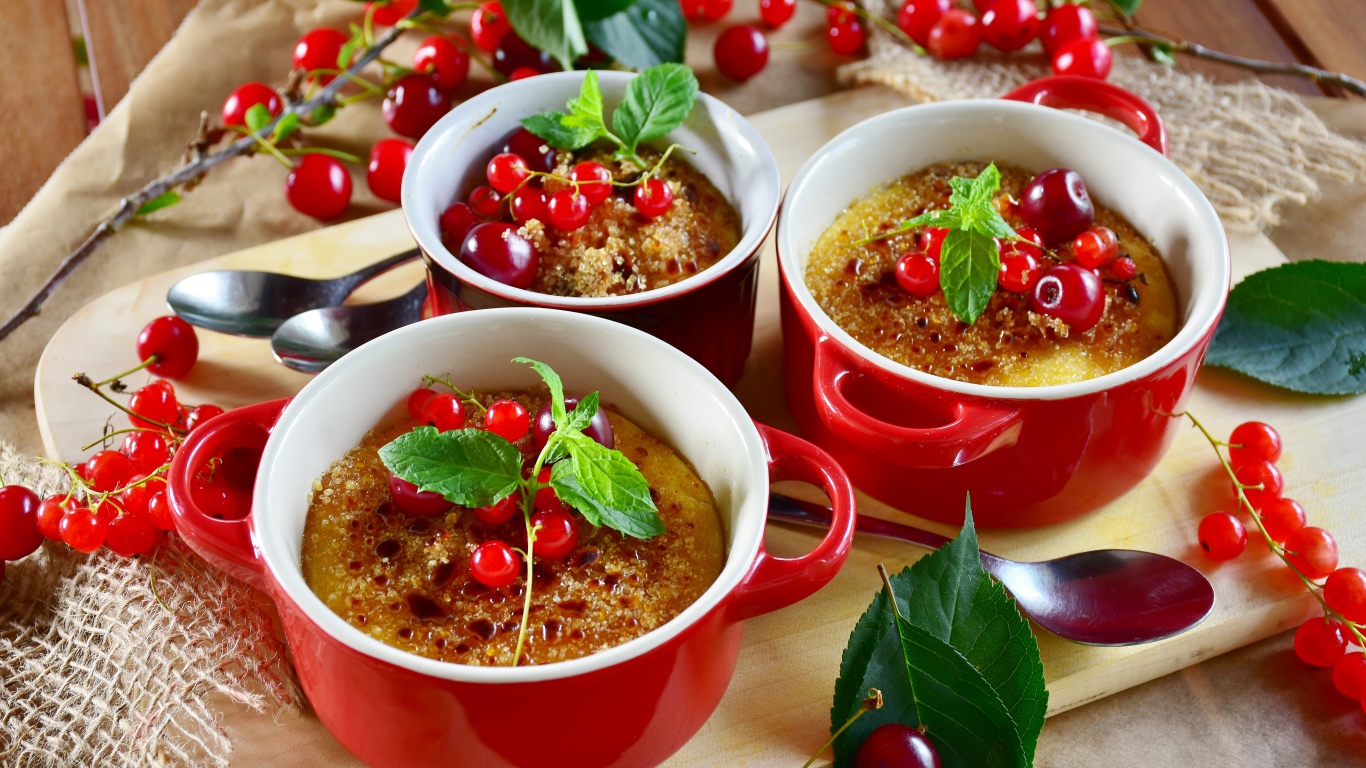 Десерт в красной посуде на столе с вишней и красной смородиной