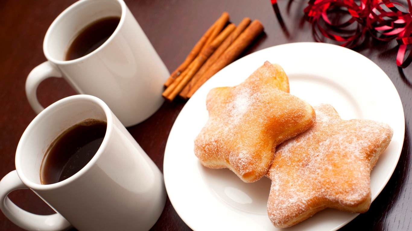 Пончики на столе с кофе и палочками корицы