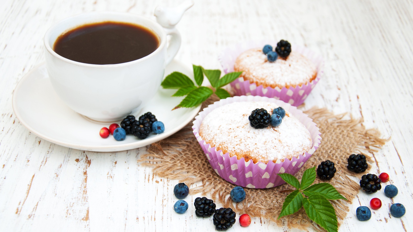 Кексы с сахарной пудрой и ягодами на столе с какао