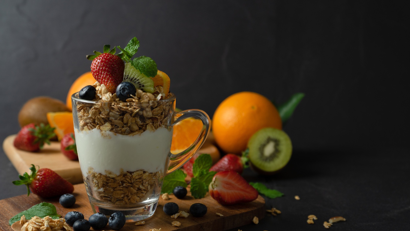 Овсяные хлопья с чашке с йогуртом на столе с ягодами и фруктами