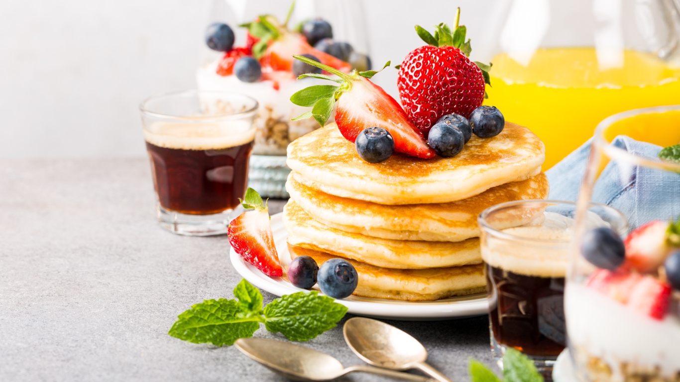 Оладьи с ягодами на столе с соком