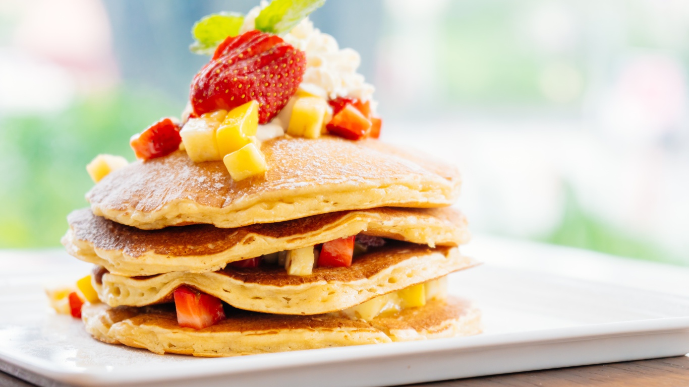 Оладьи с сахарной пудрой, сливками и кусочками клубники и ананаса