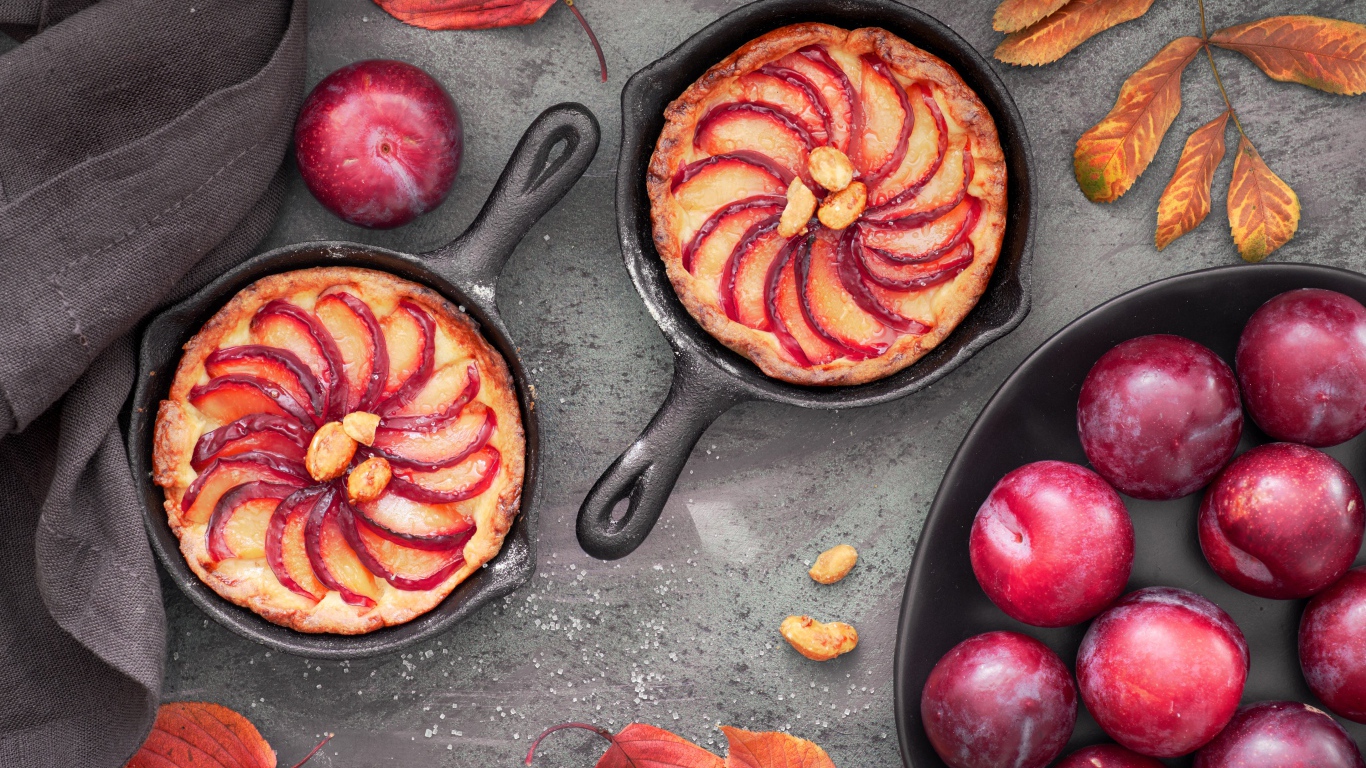 Пирог на столе с розовыми крупными сливами