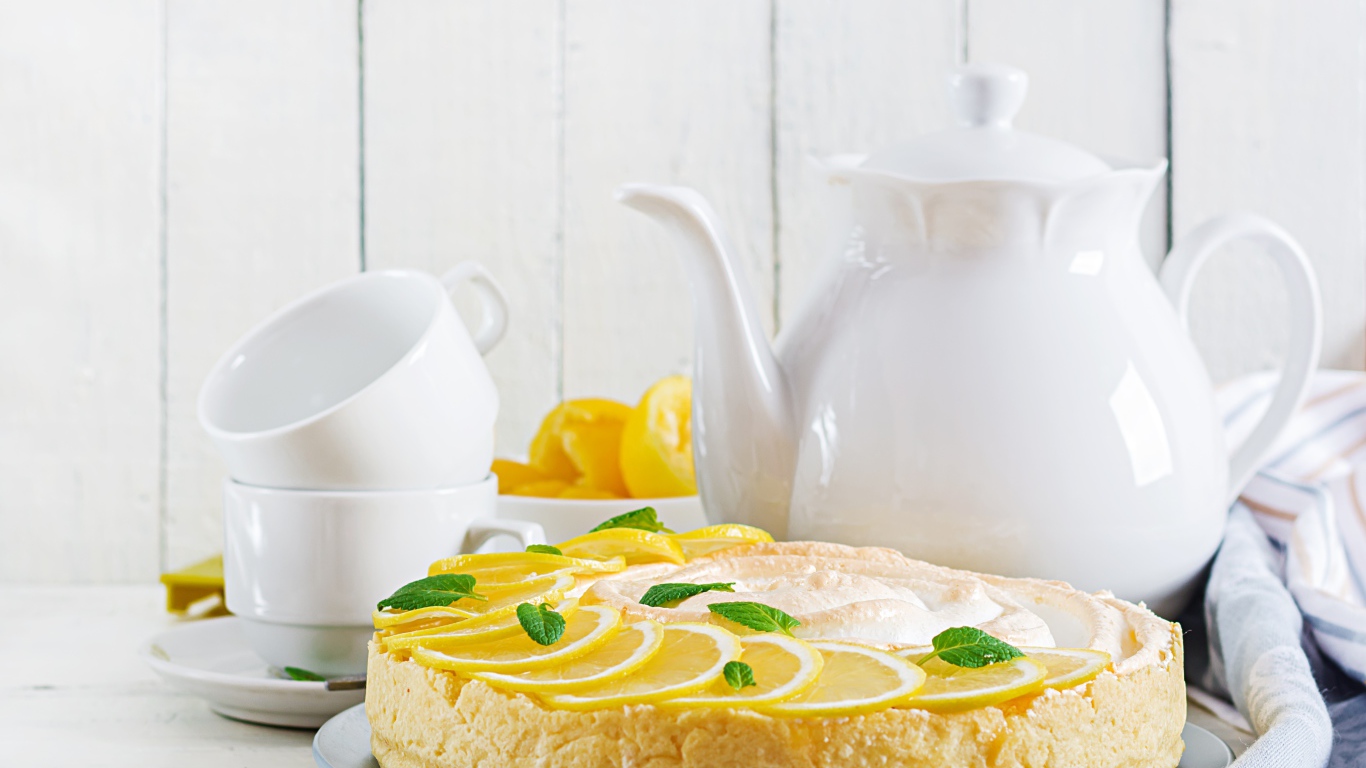 Вкусный песочный пирог с лимоном на столе с чашками и чайником