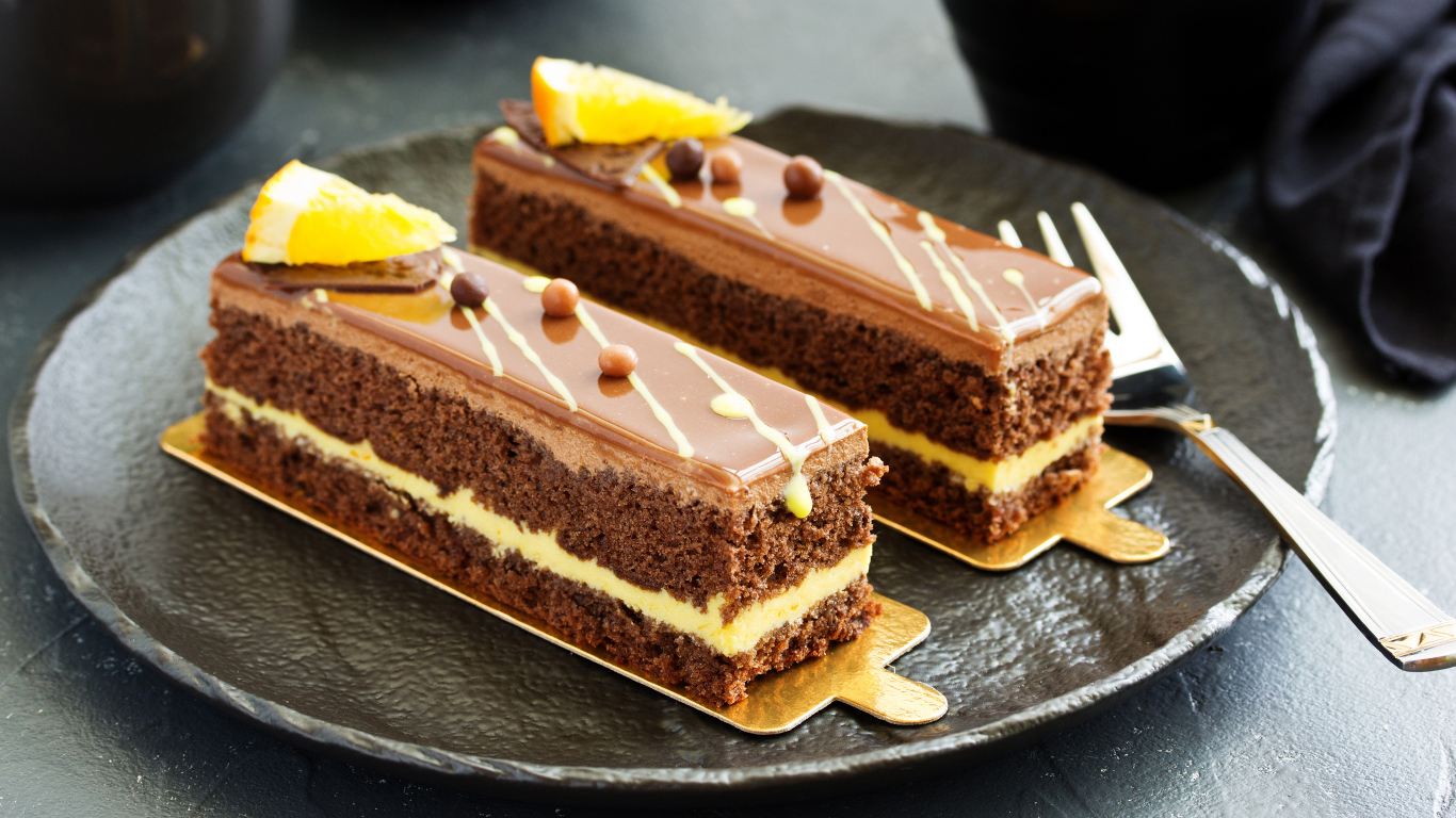 Два вкусных шоколадных пирожный на большой тарелке с вилкой