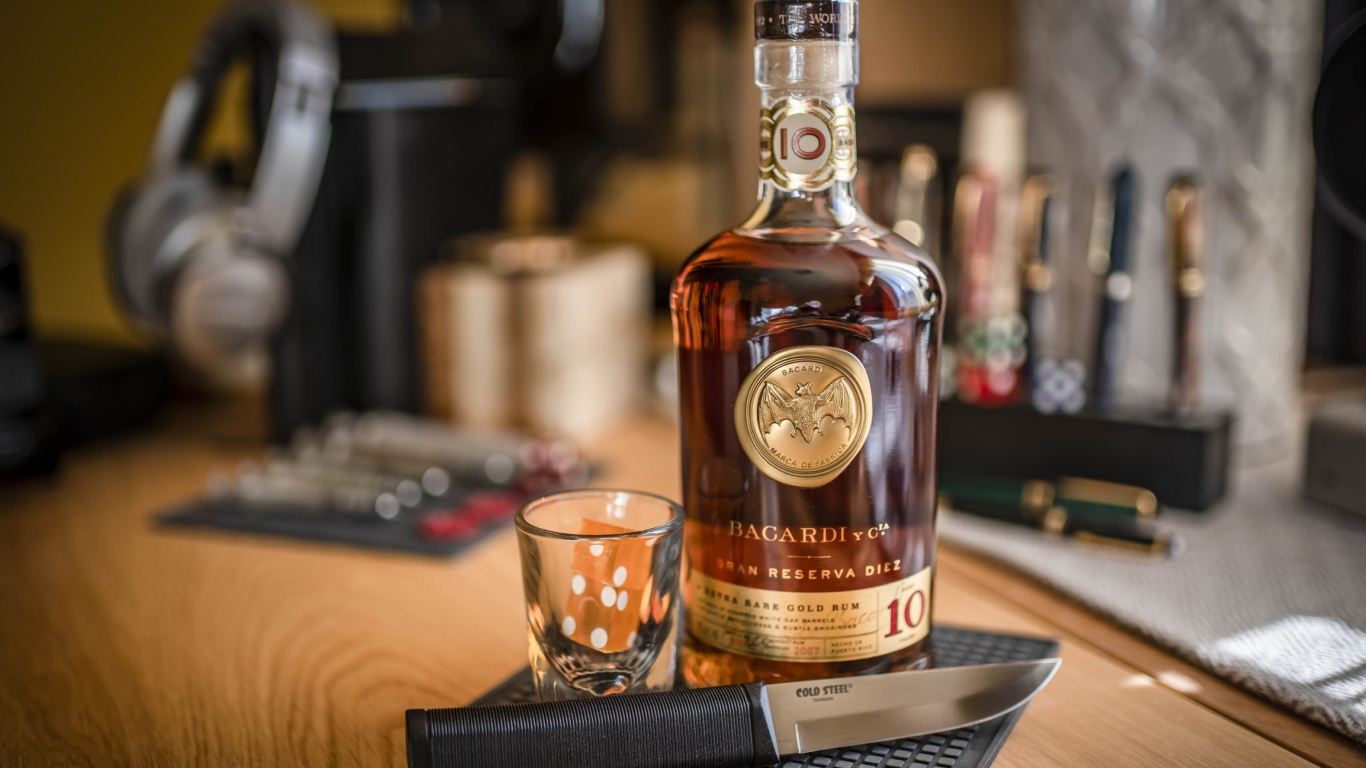 Бутылка виски на столе с рюмкой и ножом