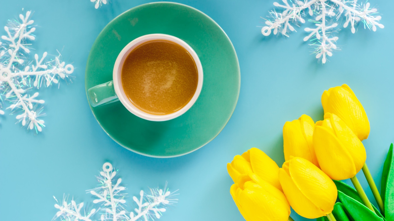 Чашка кофе на голубом фоне со снежинками и букетом желтых тюльпанов