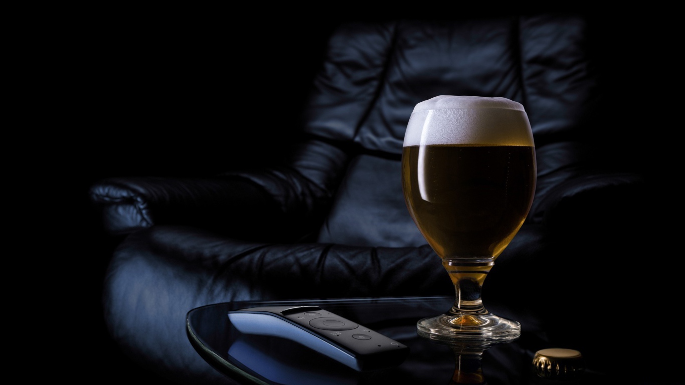 Бокал пива на фоне черного кожаного кресла