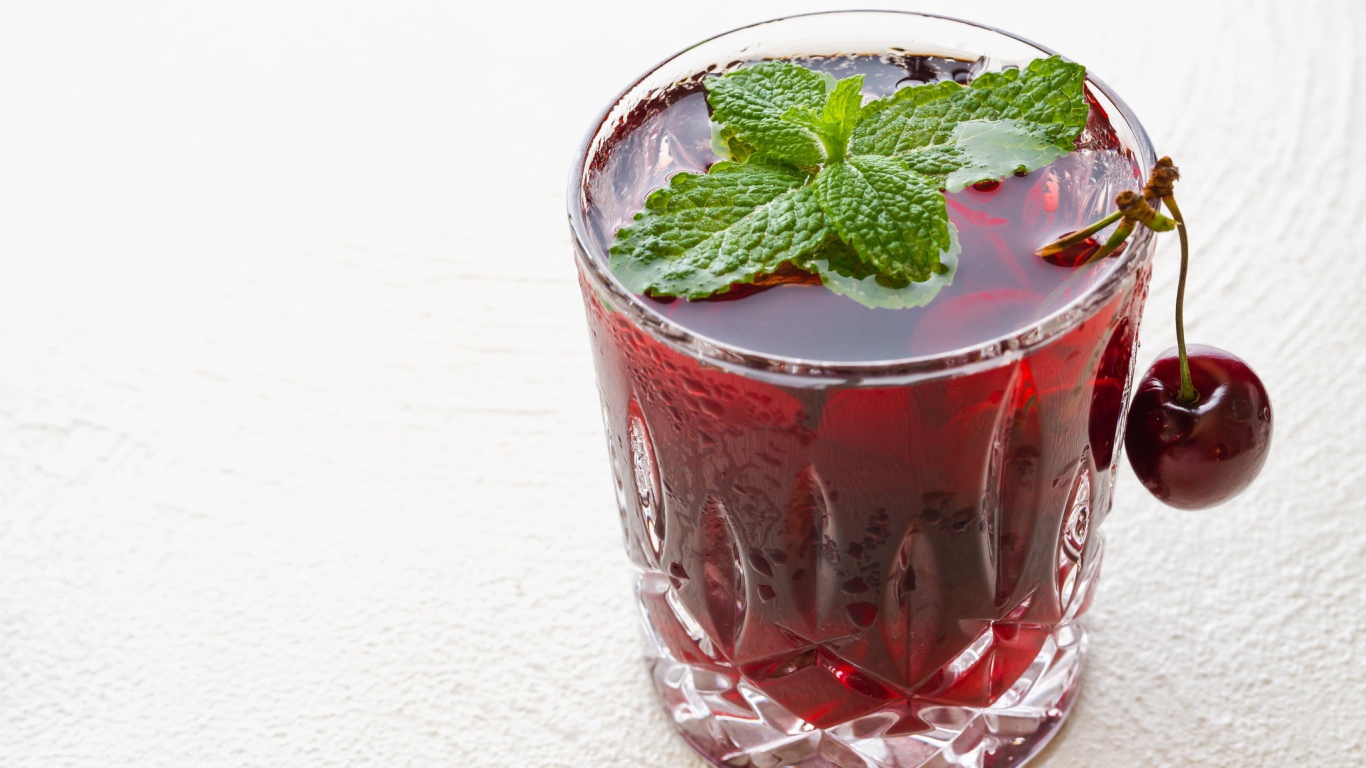 Стакан вишневого сока с мятой на белом фоне