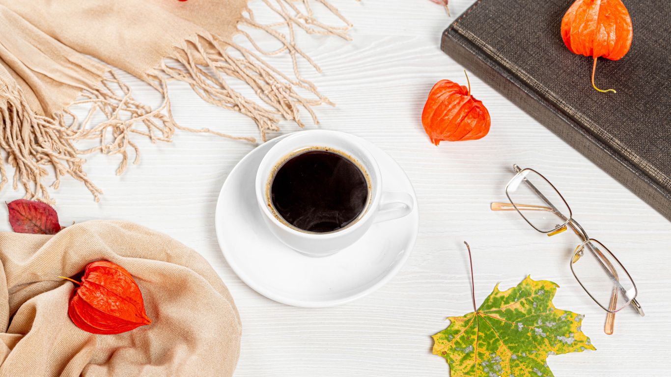 Чашка кофе на столе с книгой, очками и физалисом