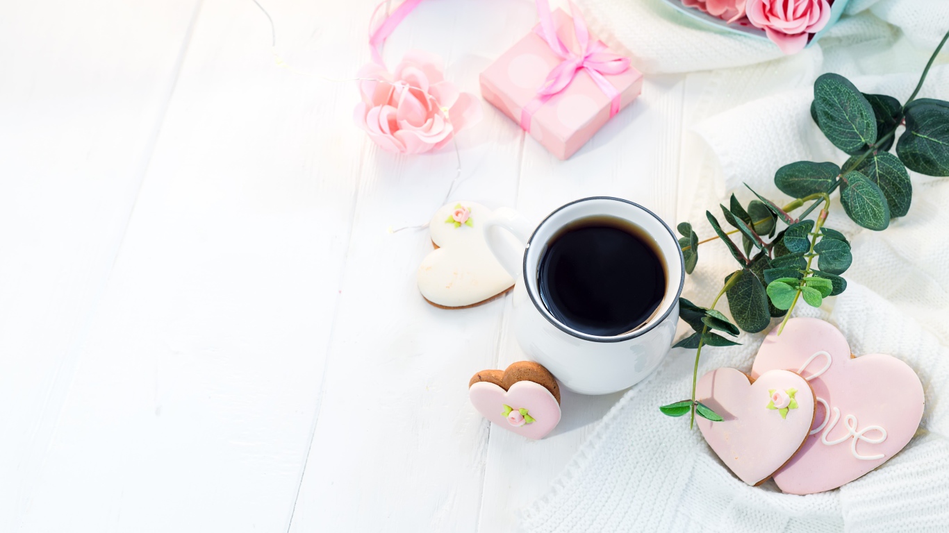 Чашка кофе на столе с печеньем в форме сердца и подарком