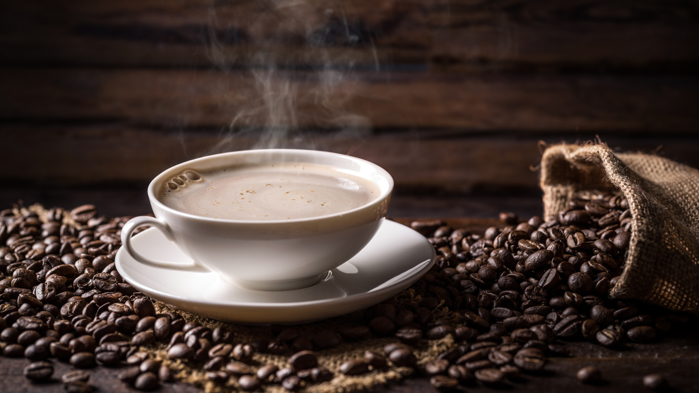 Чашка горячего ароматного кофе на столе с зернами
