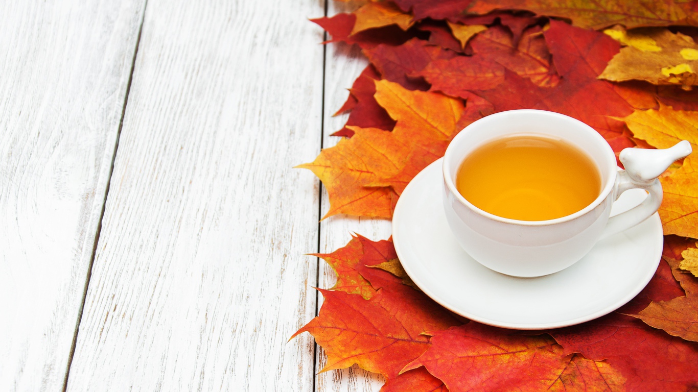 Чашка чая на столе с осенней листвой 