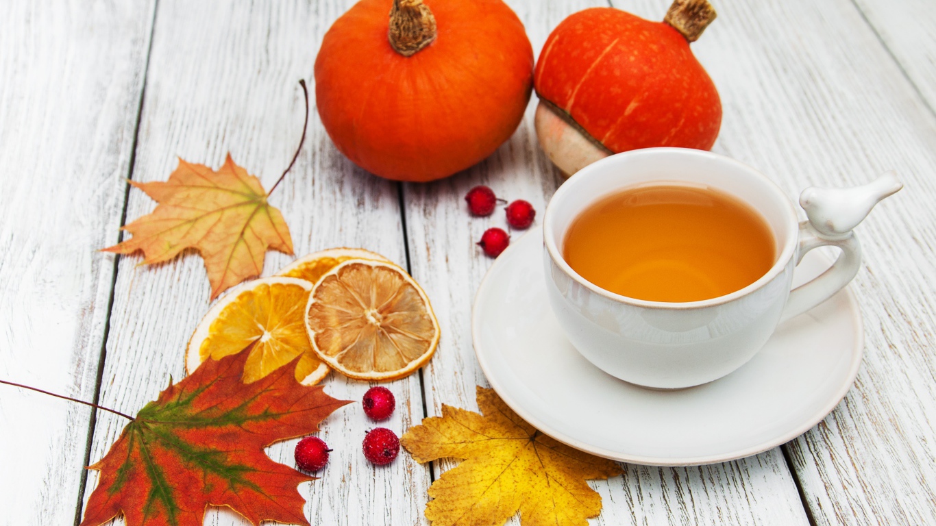 Чашка чая на столе с опавшими листьями и тыквой