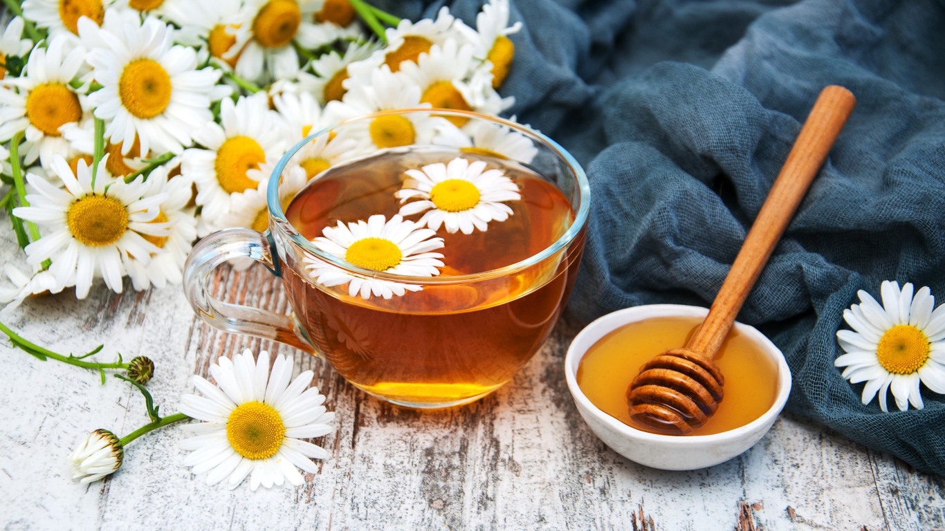 Чашка чая на столе с медом и букетом ромашек
