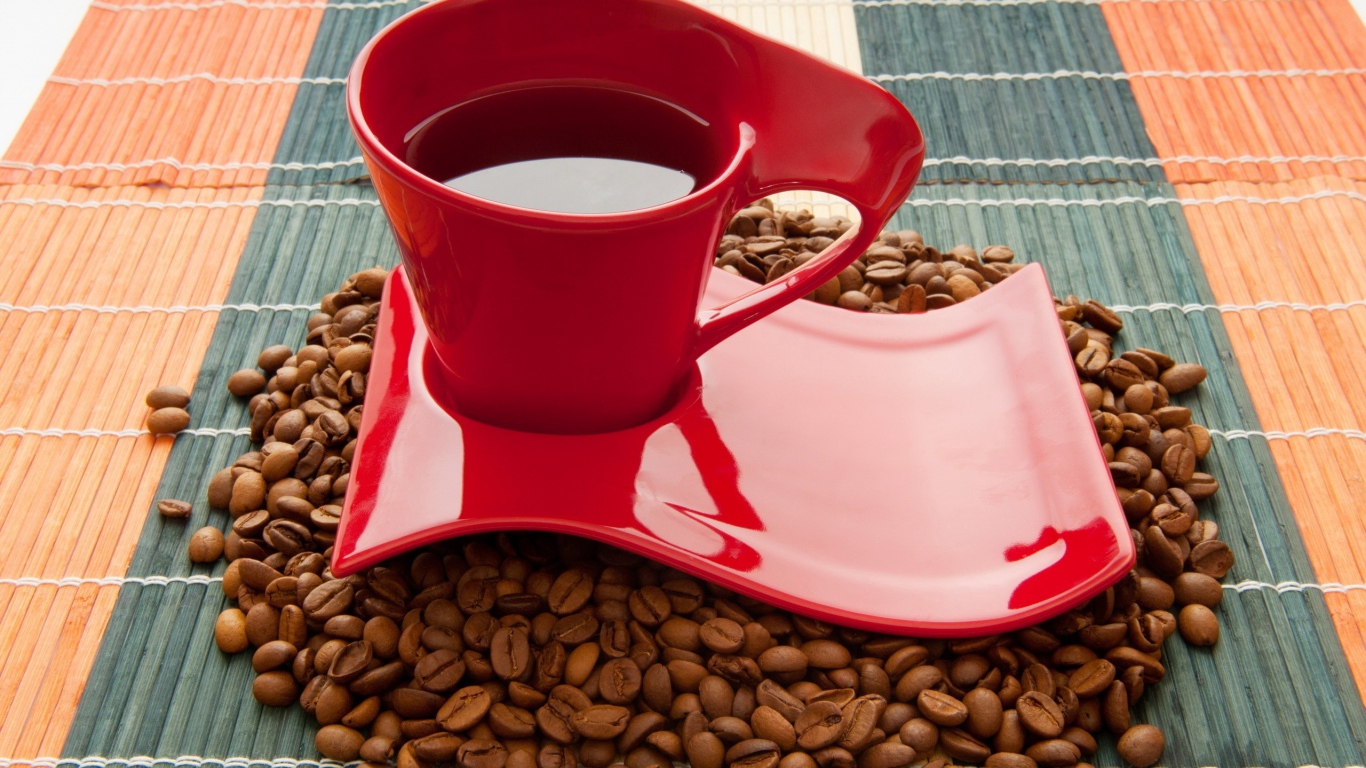 Красная чашка стоит на кофейных зернах 