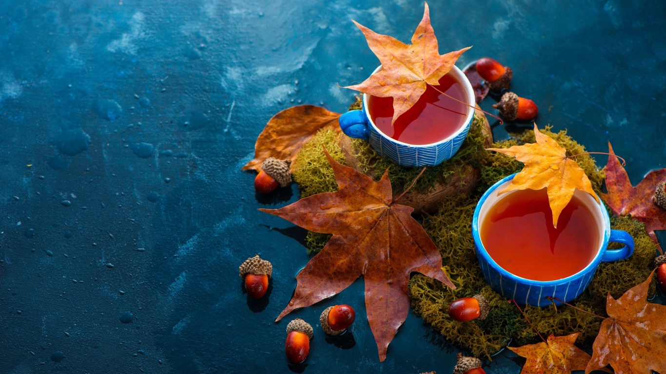Чай на столе с осенними листьями и желудями 