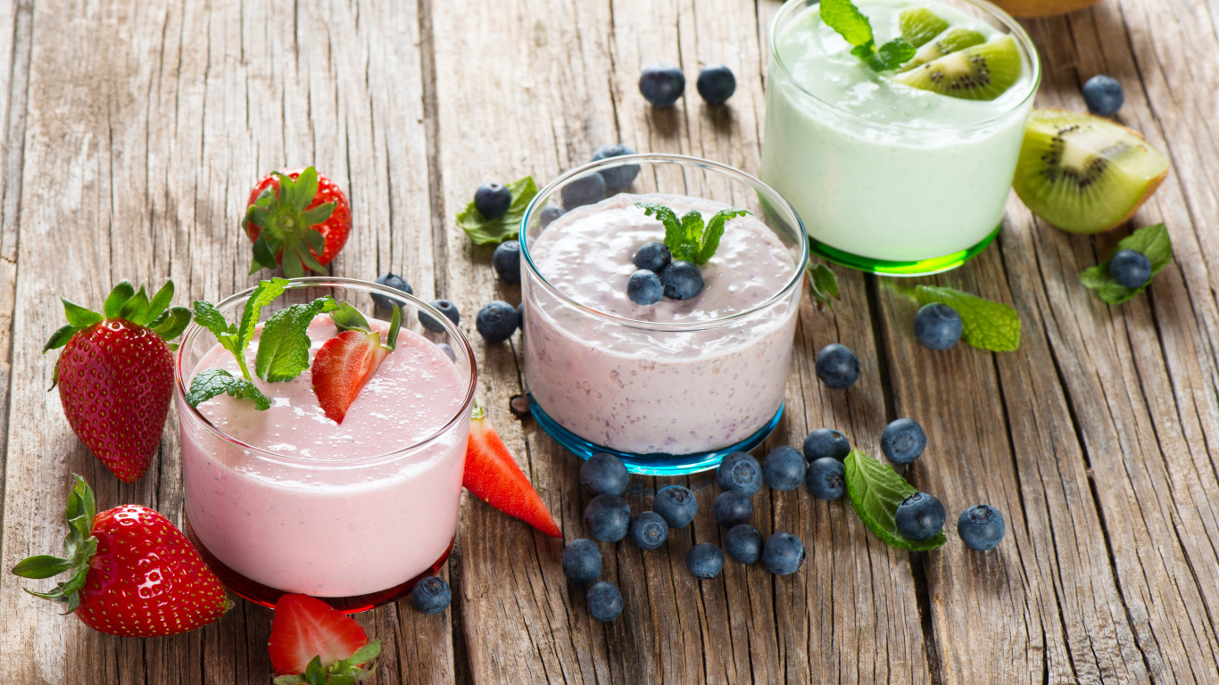 Три стакана смузи с ягодами на деревянном столе