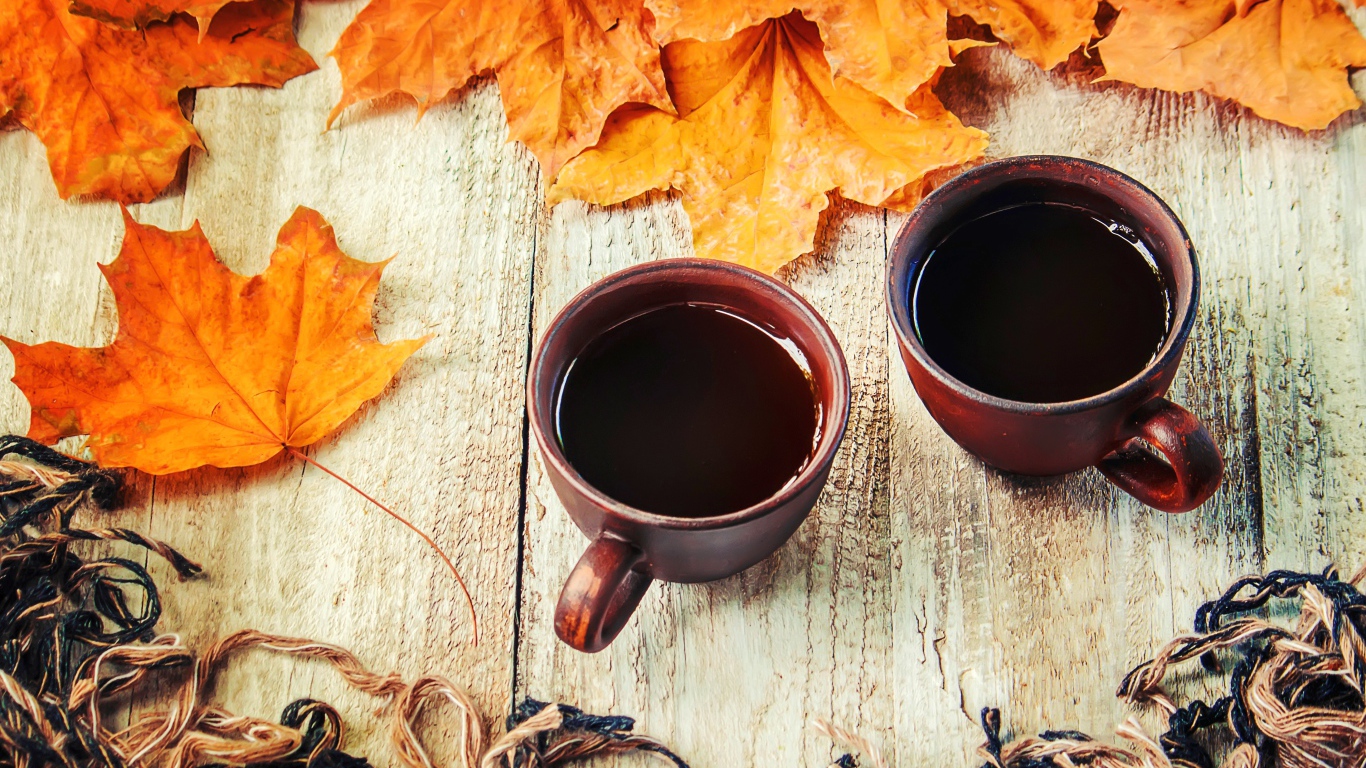 Две чашки горячего кофе на столе с сухими листьями