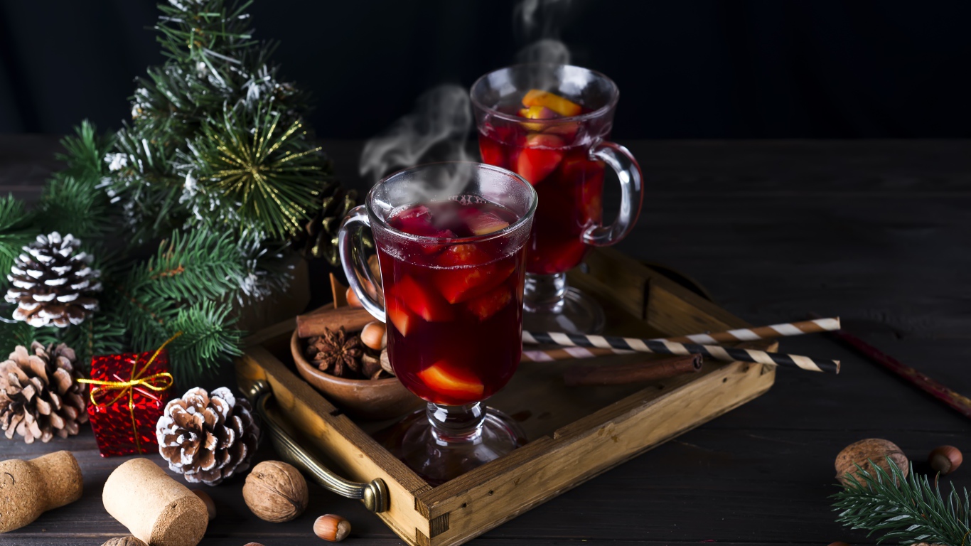 Два стакана горячего глинтвейна на столе с еловой веткой