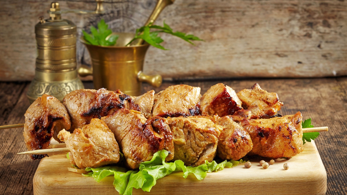 Аппетитный шашлык лежит на разделочной доске с листьями салата