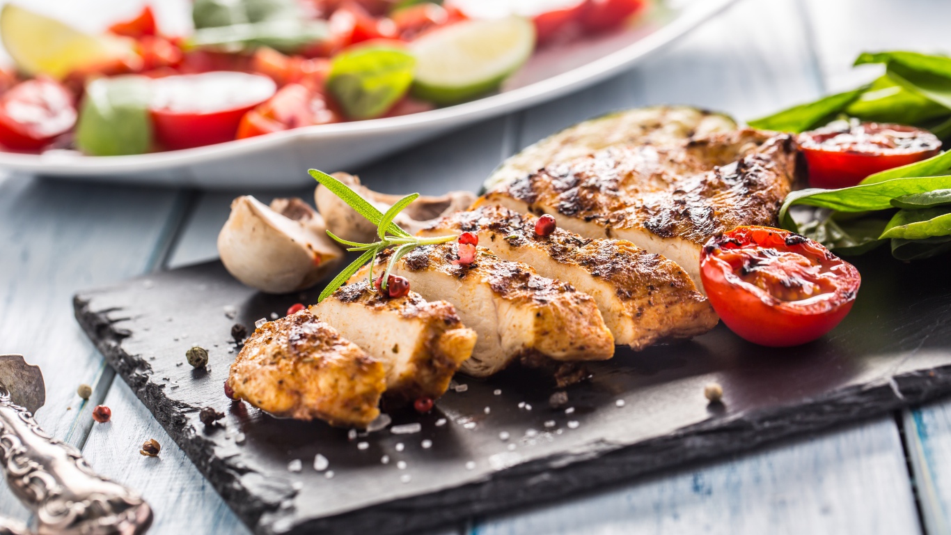 Запеченное куриное мясо на доске с помидорами 