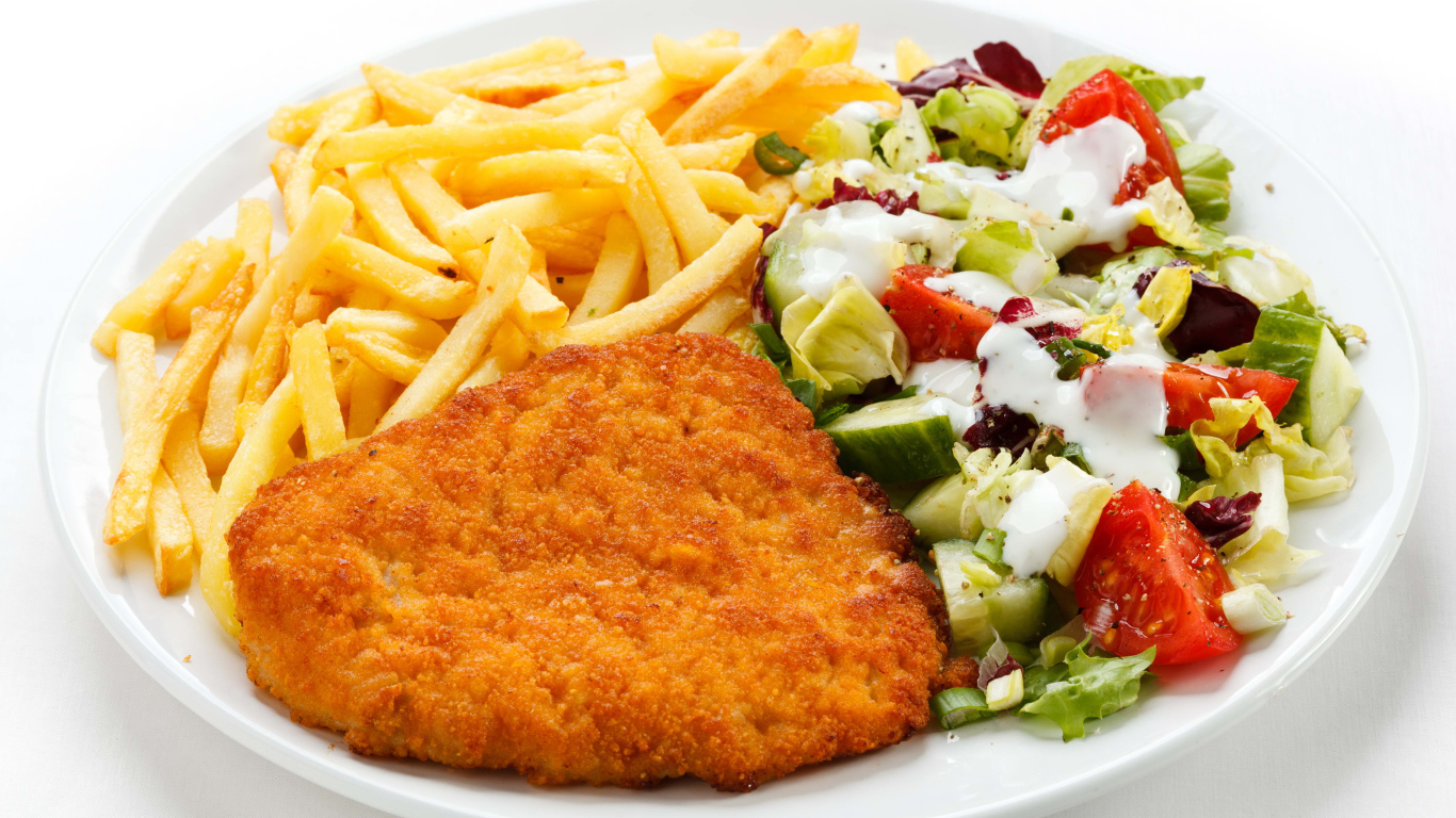 Отбивная с картофелем фри и салатом на большой белой тарелке