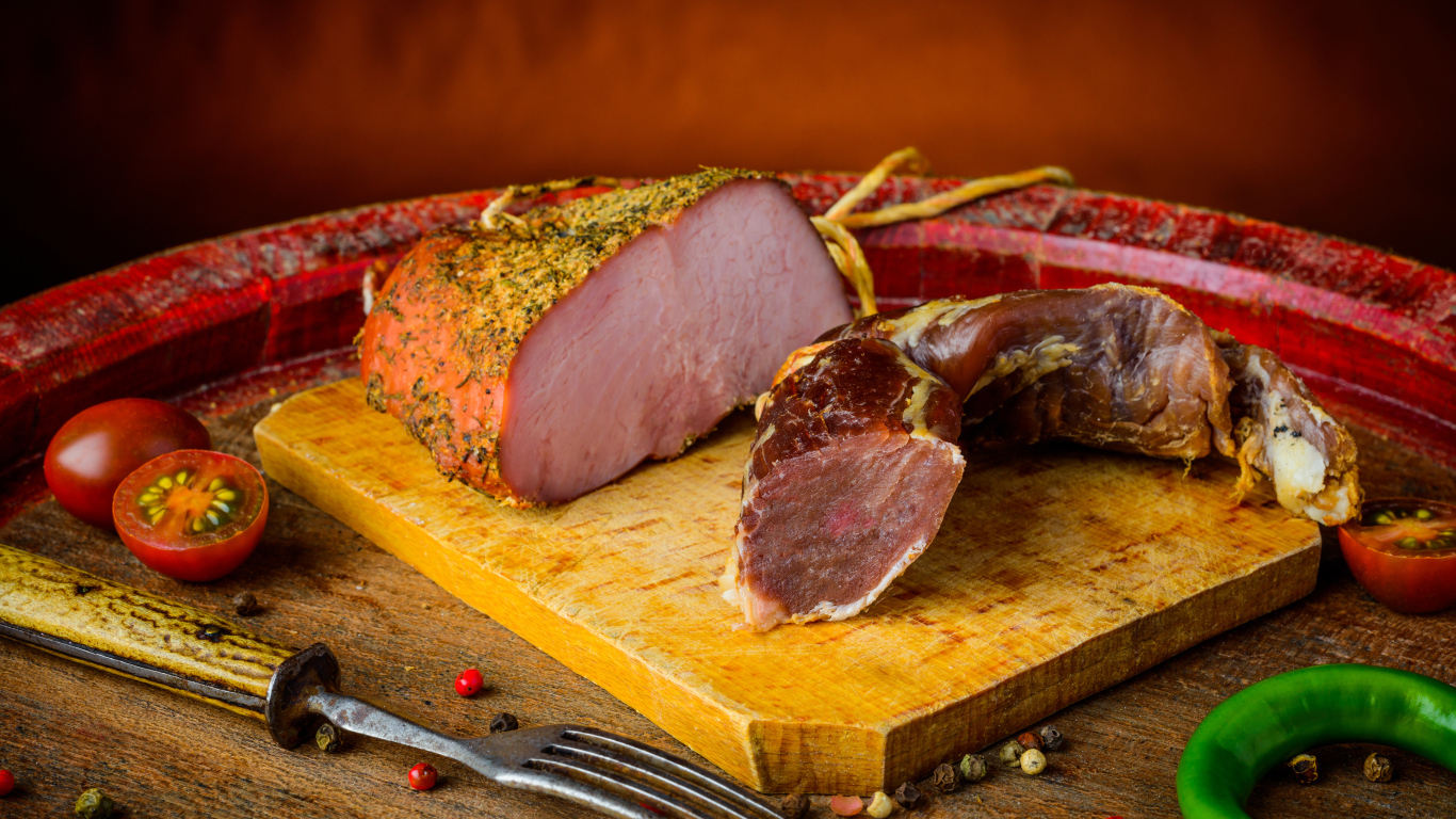 Ветчина и вяленое мясо на разделочной доске на столе с помидорами и горьким перцем 