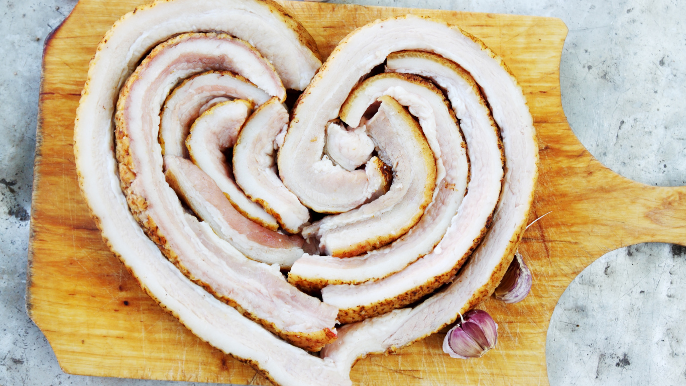 Сердце из свежего сала на доске с чесноком