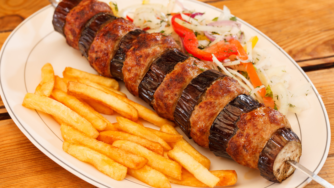 Шашлык с мясом и баклажанами на тарелке с картофелем фри 