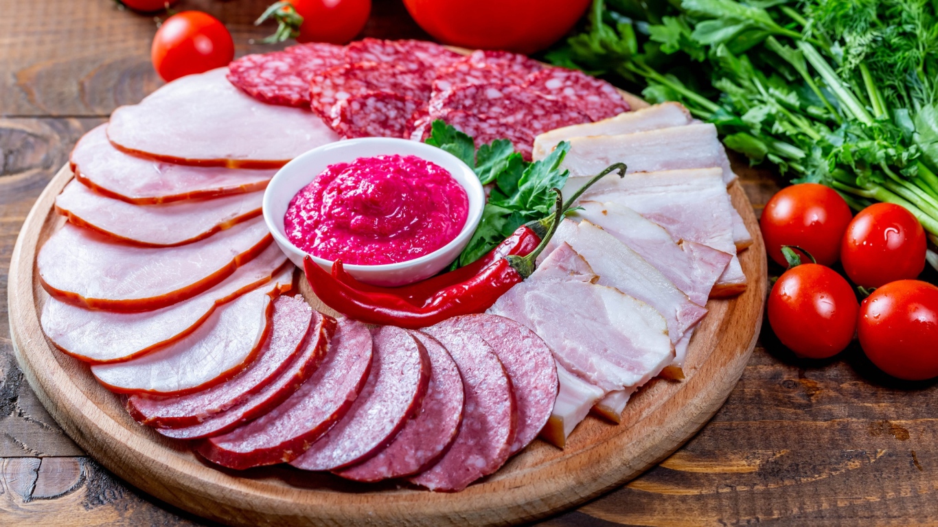 Мясная нарезка на доске с соусом, красным перцем,  помидорами и зеленью 