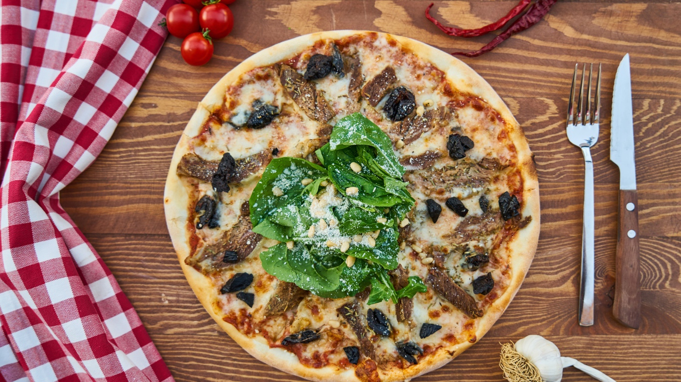 Пицца с мясом и шпинатом на столе 