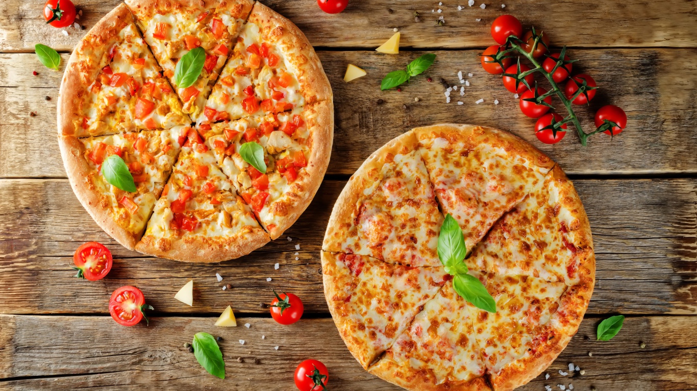 Две пиццы с сыром и болгарским перцем на столе с помидорами