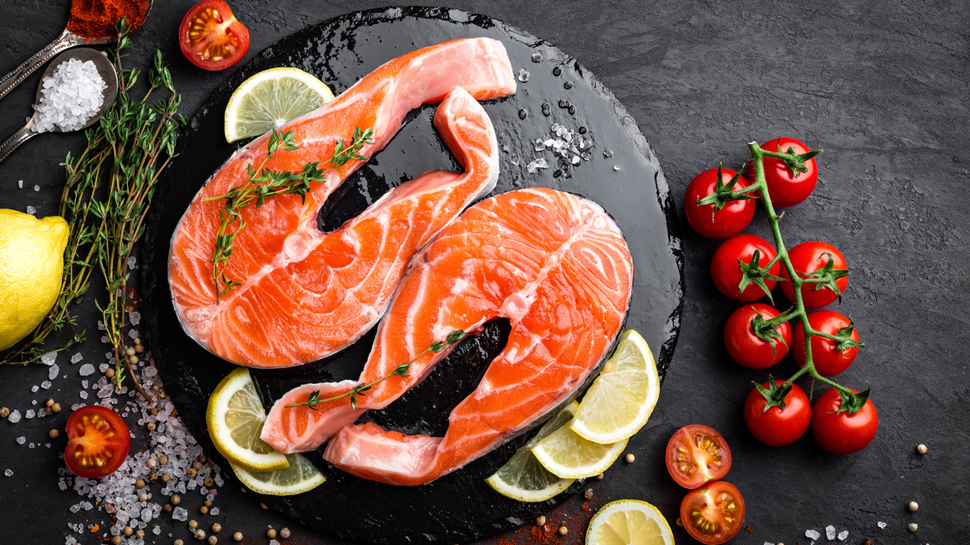 Два куска красной рыбы с овощами на черном фоне