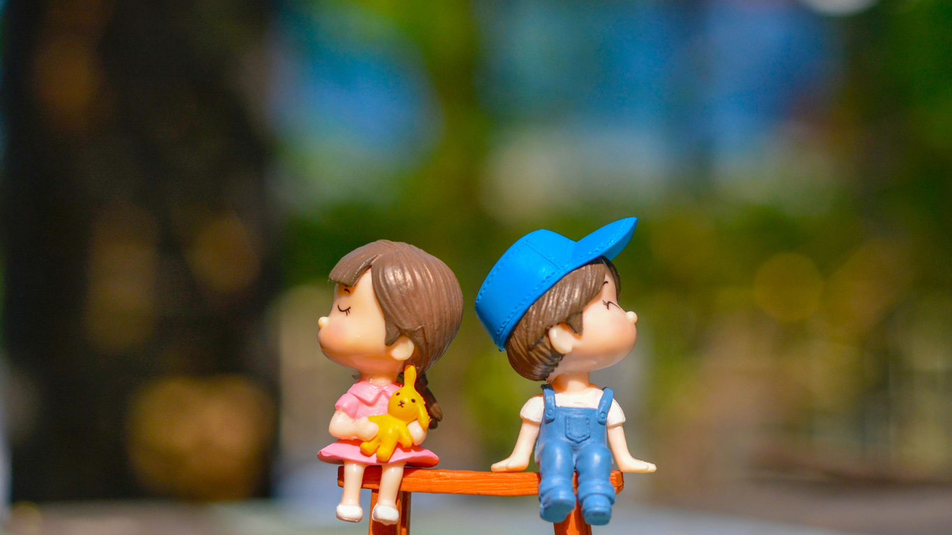 Две маленькие игрушки мальчик и девочка на лавке