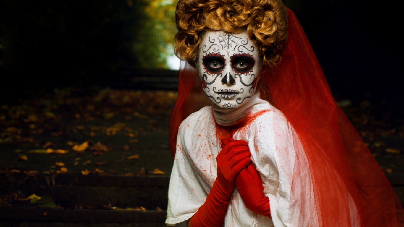 Девушка с маской на лице и красной фатой на праздник Хэллоуин 