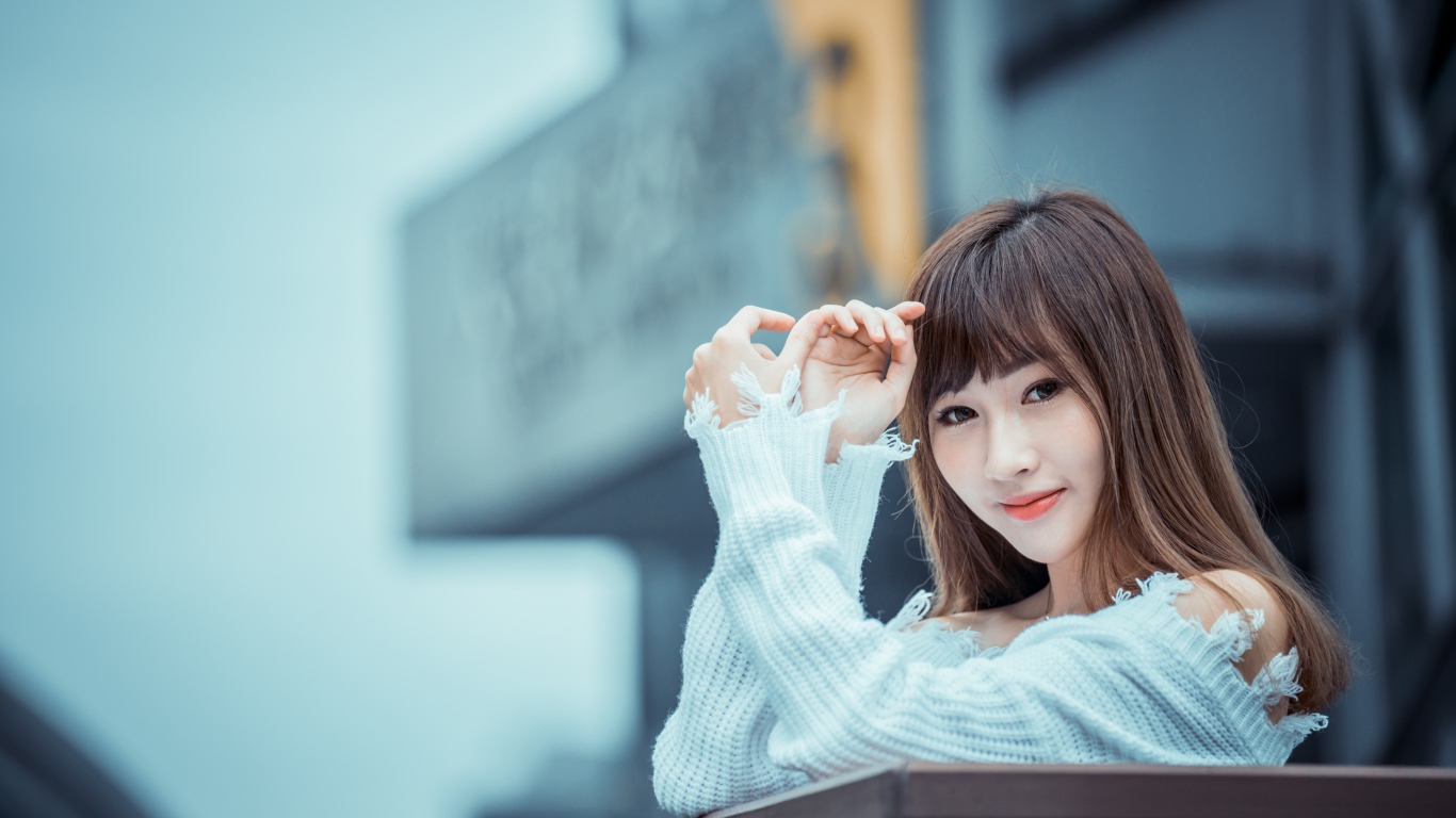 Молодая девушка азиатка в белом свитере на балконе