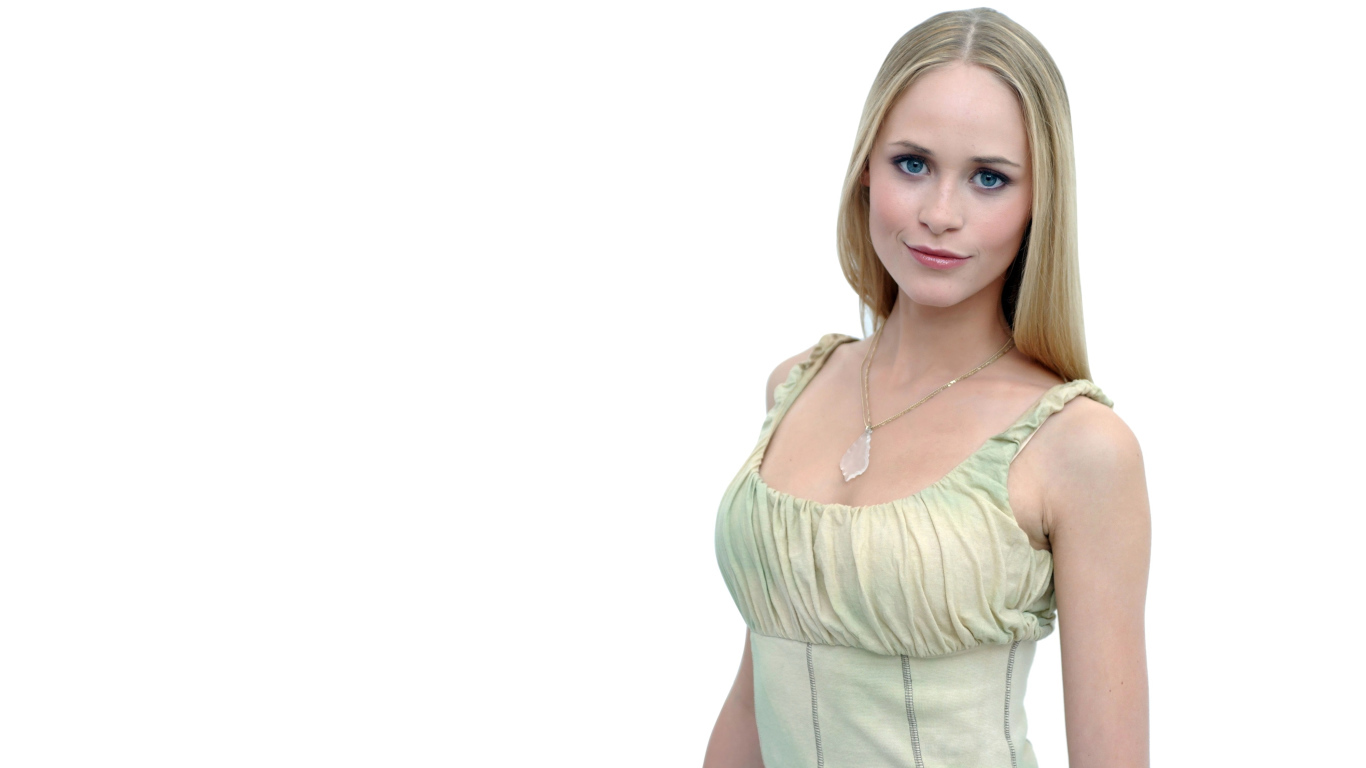 Красивая голубоглазая блондинка на белом фоне с кулоном на шее 