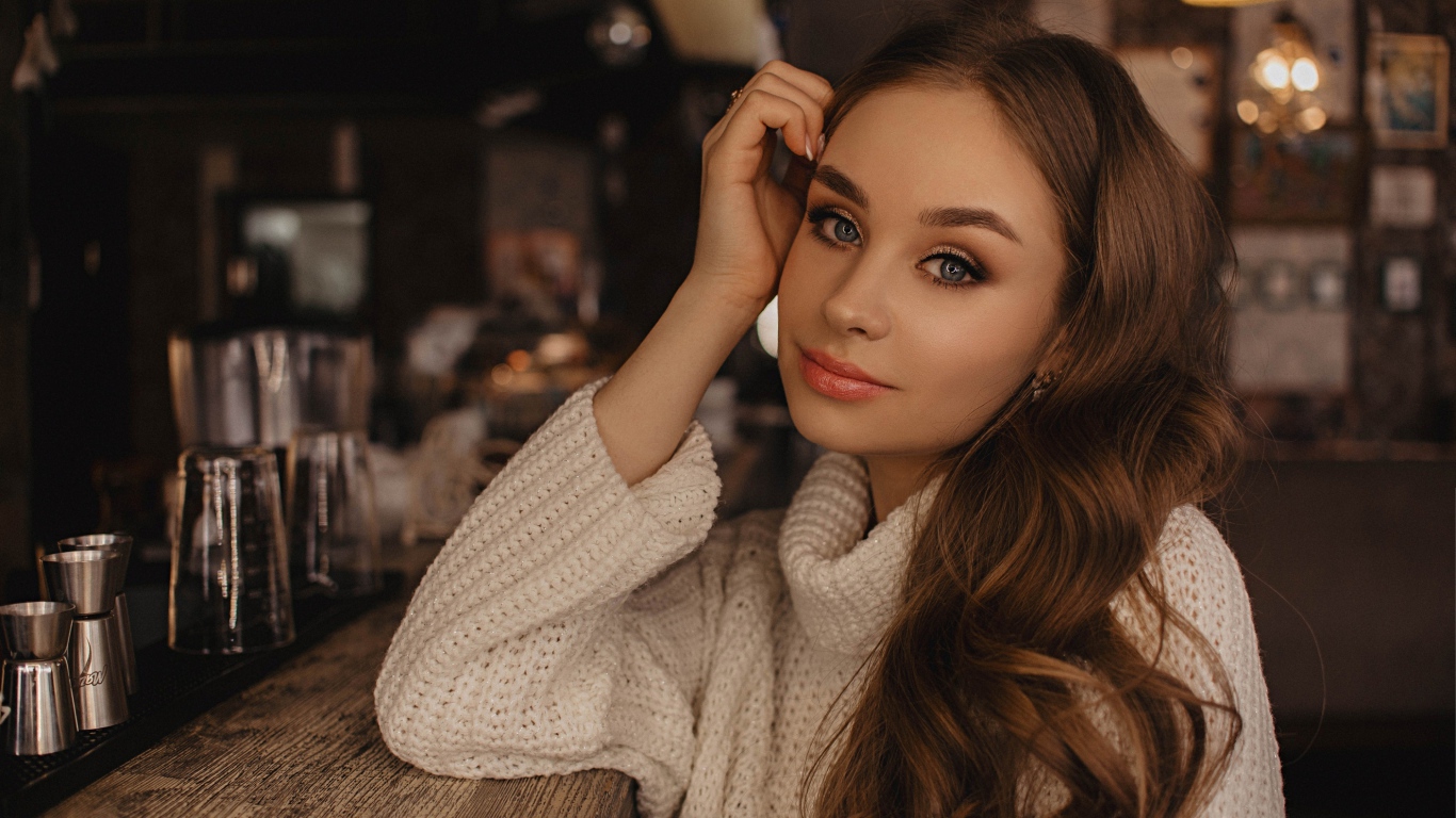 Красивая голубоглазая девушка в белом свитере в кафе